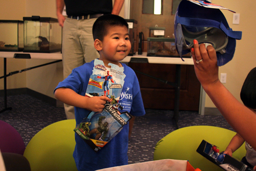 Reuben receiving superhero themed gifts from Make A Wish.